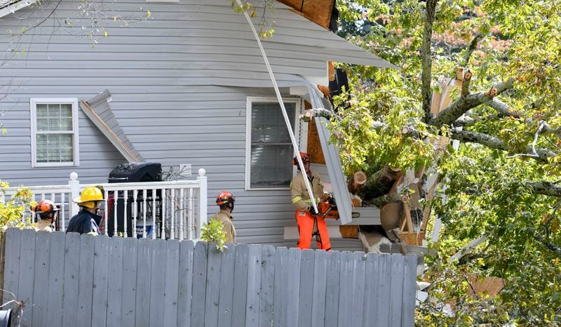 Fire crews work to remove the tree from the house Thursday afternoon.