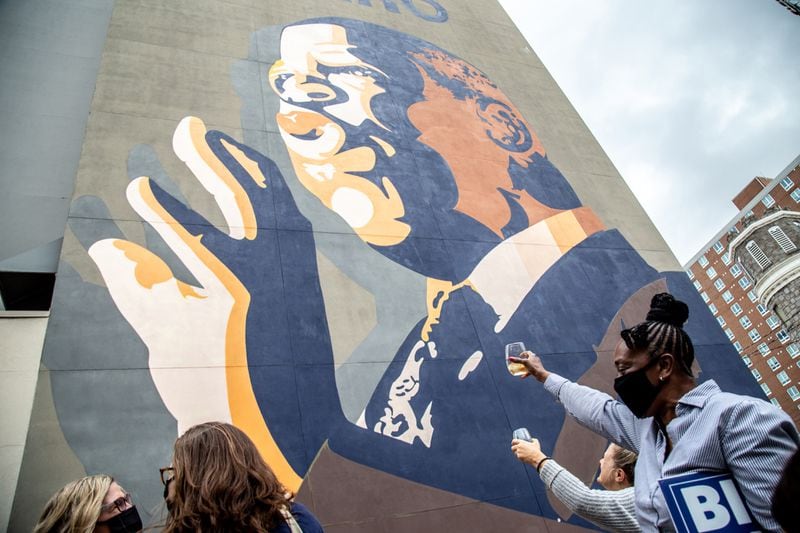 People raise a glass of champagne to the John Lewis mural after the election was called for Joe Biden Saturday, Nov. 7, 2020 in Atlanta, Georgia. (Steve Schaefer/Atlanta Journal-Constitution/TNS)