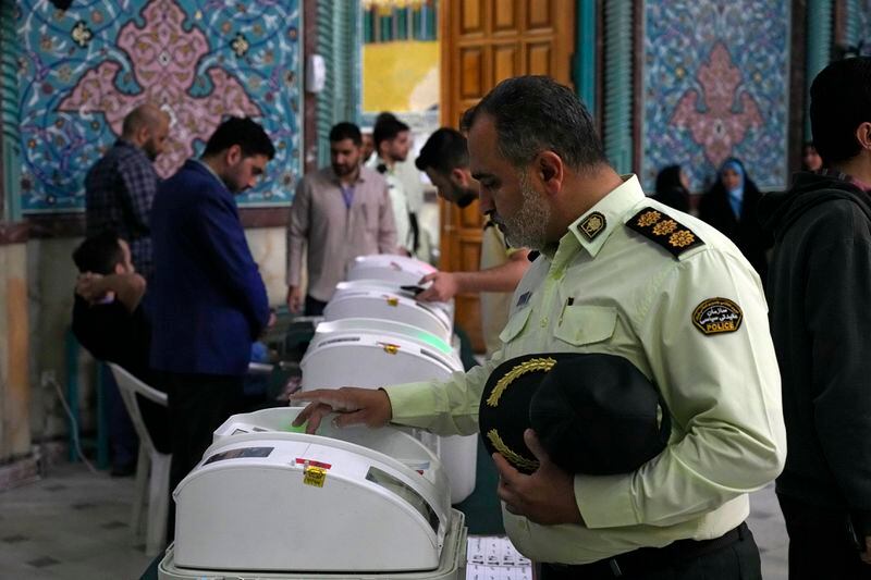 An Iranian police colonel votes for the parliamentary runoff elections at a polling station in Tehran, Iran, Friday, May 10, 2024. Iranians voted Friday in a runoff election for the remaining seats in the country's parliament after hard-line politicians dominated March balloting. (AP Photo/Vahid Salemi)