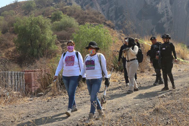 Women carry digging tools where they found a clandestine crematorium in Tlahuac, on the edge of Mexico City, Wednesday, May 1, 2024. Ceci Flores, a leader of one of the groups of so-called "searching mothers" from northern Mexico, announced late Tuesday that her team had found bones around clandestine burial pits and ID cards, and prosecutors said they were investigating to determine the nature of the remains found. (AP Photo/Ginnette Riquelme)