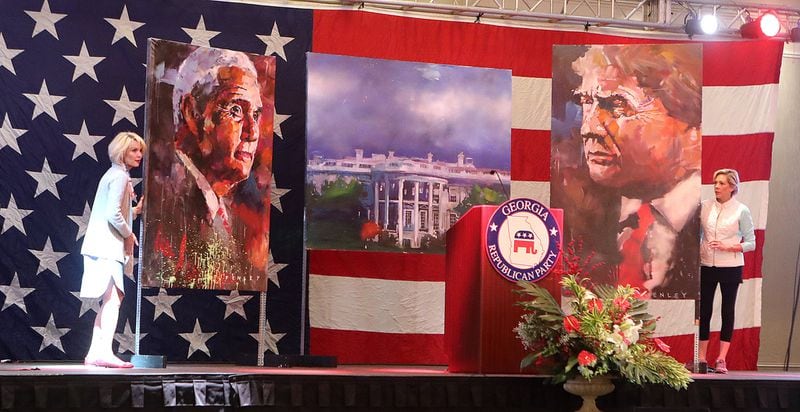 Ginger Howard (left) and Lee Anne Cowart set the stage with paintings of Donald Trump and Mike Pence for the Republican watch party Tuesday at the Grand Hyatt in Buckhead. Curtis Compton /ccompton@ajc.com