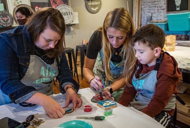 Employee Kate Dabson (C) works with Katy Nichols and her son Hiden (6) to make decorations at an AR Workshop during Small Business Saturday in Smyrna November 27, 2021.  STEVE SCHAEFER FOR THE ATLANTA JOURNAL-CONSTITUTION