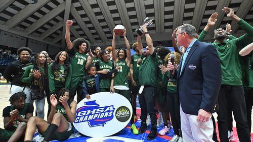 Grayson head coach Geoffrey Pierce holds up the trophy as he celebrates with players after his team defeated McEachern 51-41 Saturday in the Class 7A boys championship game. (Hyosub Shin/hshin@ajc.com)