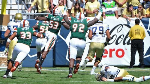 Georgia Tech Yellow Jackets quarterback Justin Thomas (foreground) falls down as Miami Hurricanes linebacker Shaquille Quarterman (55) runs for a touchdown after he stole the ball from Justin Thomas in the first half at Bobby Dodd Stadium on Saturday, October 1, 2016. HYOSUB SHIN / HSHIN@AJC.COM
