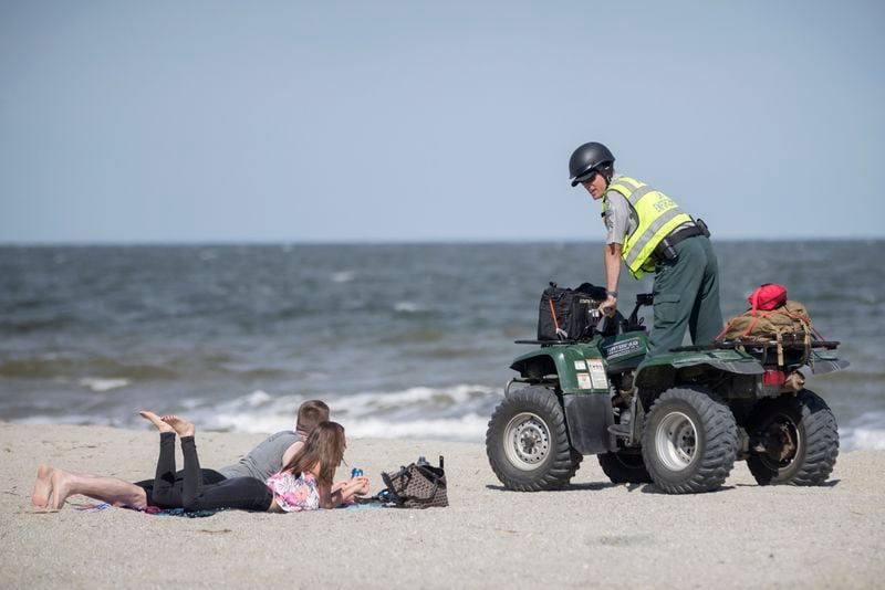 TYBEE ISLAND, GA - APRIL 4, 2020: Georgia Department of Natural Resources Law Enforcement Division Corporal Barry Britt, right, enforce Gov. Brian Kemp's order to open the beaches on Tybee Island allowing people to exercise outside, with social distancing of at least 6 feet. (AJC Photo/Stephen B. Morton)