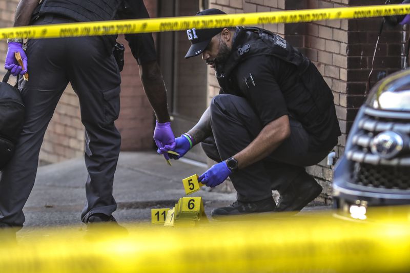 Atlanta police collect shell casings from the scene of a double shooting that left one man dead last month. Atlanta police have investigated 63 homicide cases in 2021, a 58% increase over this time last year. 
