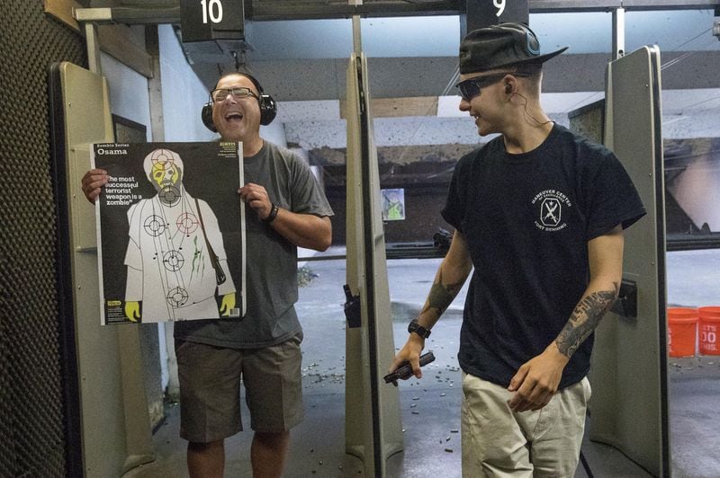 Dalton Peters, right, laughs as his father, Chris, shows off his target during a family outing at Hi-Caliber Firearms in Canton, Wednesday, June 27, 2018. Dalton is one of about 2,200 Georgia National Guardsmen who will deploy to Afghanistan with the 48th Brigade in the coming months. (ALYSSA POINTER/ALYSSA.POINTER@AJC.COM)