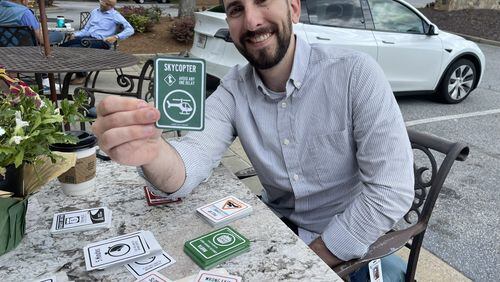 "Atlanta Traffic: The Card Game" creator Evan Simmons demonstrates his clever, humorous card game at a Roswell coffee shop on May 15th, 2024." Credit: Doug Turnbull/WSB Traffic