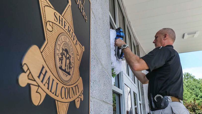 Hall County deputy T. Abercrombie installs wreaths on the front of the Sheriff’s office after losing a fellow deputy in the line of duty. The Hall County sheriff’s deputy killed in a shootout late Sunday night was 28-year-old Nicolas Dixon. JOHN SPINK/JSPINK@AJC.COM