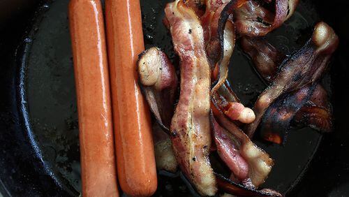 MIAMI, FL - OCTOBER 26: In this photo illustration, processed meats, including hotdogs and bacon, cook in a frying pan on October 26, 2015 in Miami, Florida. A report released today by the World Health Organisation's International Agency for Research on Cancer announced that eating processed meat can lead to colorectal cancer in humans even as it remains a small chance but rises with the amount consumed. (Photo illustration by Joe Raedle/Getty Images)