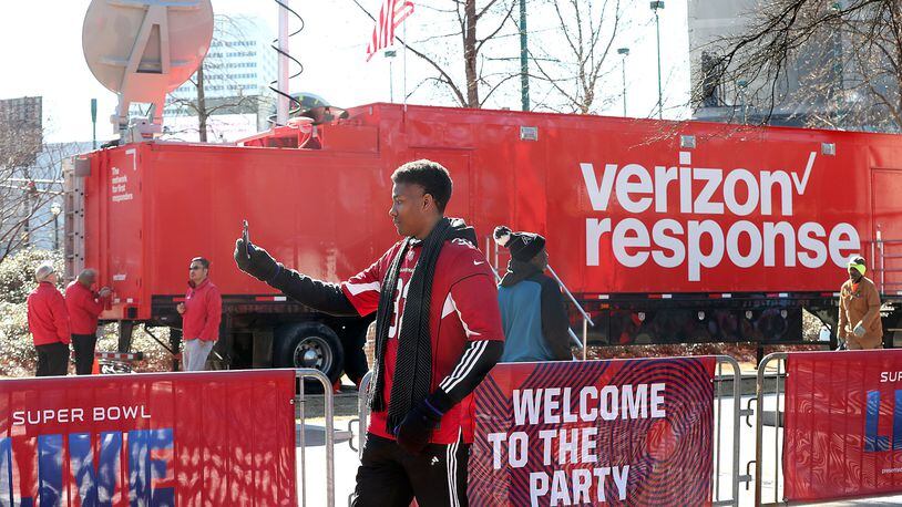 Jan. 31, 2019 Atlanta: Merrion Mitchner, Buford, snaps a photo on his cell phone outside Super Bowl Live at Centennial Olympic Park beside a Verizon response tractor trailer truck on Thursday, Jan. 31, 2019, in Atlanta. The crunch of Super Bowl fans flooding into downtown Atlanta is prompting wireless providers like Verizon to boost their capacity in order to keep the calls and texts moving during the big game. Curtis Compton/ccompton@ajc.com