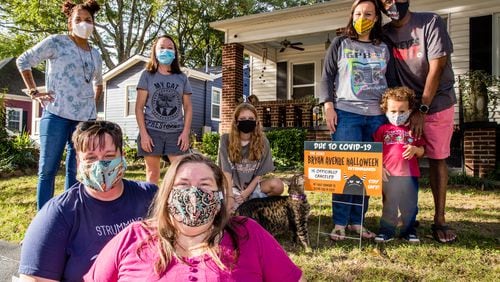 The East Point neighborhood around Bryan Avenue replaces Halloween decorations with yard signs announcing the 2020 extravaganza is canceled.  The close-knit community includes Shannon Korta, from top left, Joann Richardson, Reagan Fizell; the Hackshaw family Emmalee, Kevin and 3-year-old Elliott; with Andria Towne, front left, and Sheila Merritt. Jenni Girtman for The AJC