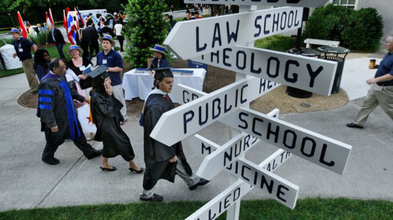 Graduates move into place Monday for graduation ceremonies at Emory University as signs point the way Commencement took place on the Emory quadrangle for about 3,900 graduates. About 15,000 people attended.