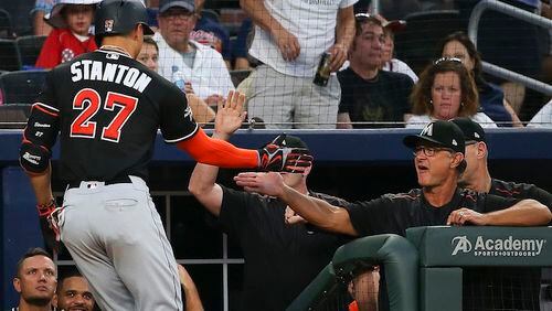 Miami Marlins right fielder Giancarlo Stanton (27), iS greeted at the dugout by manager Don Mattingly after hitting a solo home run in the sixth inning of a baseball game against the Atlanta Braves, Saturday, Aug. 5, 2017, in Atlanta. (AP Photo/John Bazemore)