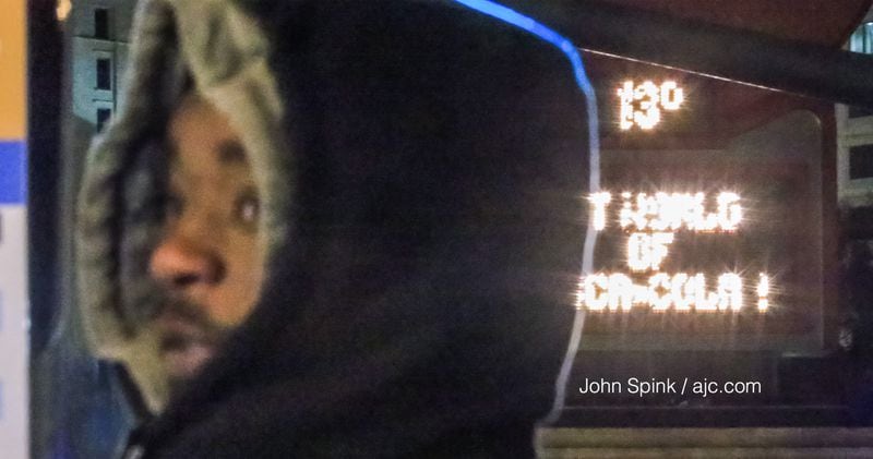 Dominique Patterson waits on Peachtree Street for a bus early Tuesday. The Coca-Cola sign says it all: 13 degrees in Atlanta. JOHN SPINK / JSPINK@AJC.COM