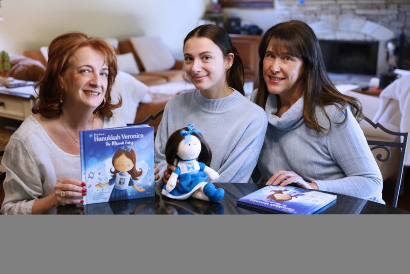  Julie Anne Cooper, left, is pictured with her daughter Lucy Cooper and co-author Wendy Brant. Cooper made the doll 14  years ago for her then-kindergarten age daughter who came home from school during holiday season asking for Christmas elf as a toy. Miguel Martinez / miguel.martinezjimenez@ajc.com