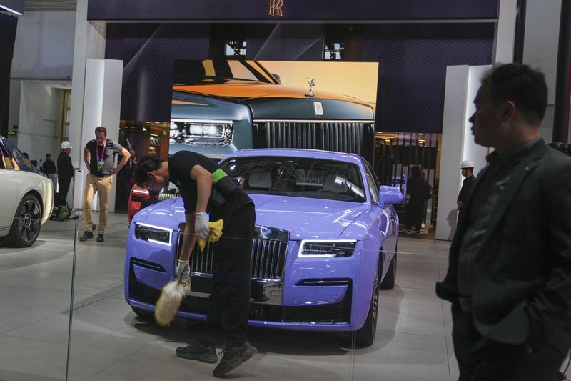 Workers prepare at a Rolls Royce car booth for the upcoming auto show to be held in Beijing, China, Wednesday, April 24, 2024. Foreign automakers have been caught flat-footed in China by an electric vehicle boom that has shaken up the market over the last three years. That has left manufacturers like Volkswagen scrambling to develop new models for a very different market than at home. (AP Photo/Tatan Syuflana)