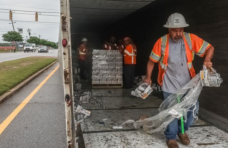 Raul Hernandez with Rhino Services helps clean up after a tractor-trailer overturned and spilled soda cans on Fulton Industrial Boulevard.