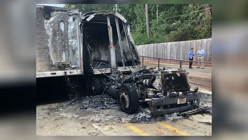 A charred Coca-Cola delivery truck sits outside a Publix after crews extinguished flames behind a DeKalb County shopping center.