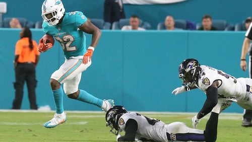 Miami Dolphins' Kenyan Drake (32) breaks away from Baltimore Ravens' Tony Jefferson (23) for a large gain to help set up a touchdown on Saturday, Aug. 25, 2018 at Hard Rock Stadium in Miami Gardens, Fla. (Charles Trainor Jr./Miami Herald/TNS)