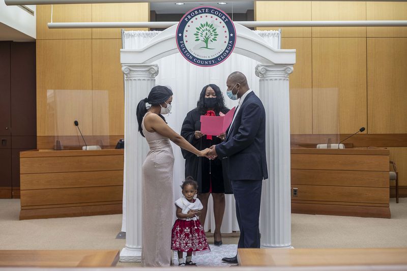 One-year-old Fatima Zara Fofana stands in between her mother and father, Naminata Doumbia, left, and Ousmane Fofana, right, as they participate in a wedding ceremony performed by Fulton County Probate Judge Kenya Johnson, center, at the Fulton County Courthouse in Atlanta, Friday, Feb. 12, 2021. (Alyssa Pointer / Alyssa.Pointer@ajc.com)