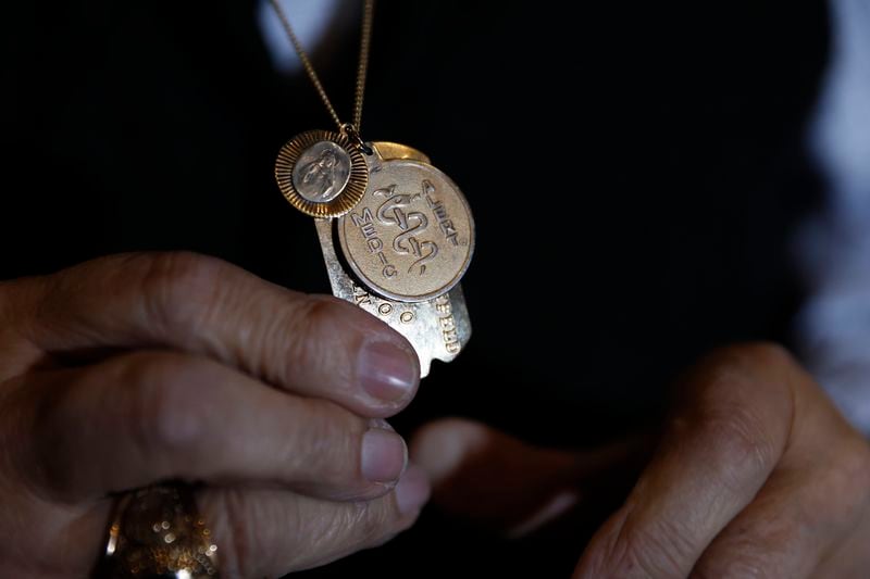 Holocaust survivor George Rishfeld shows the St. Christopher medal his Catholic rescuers gave him when they hid him in Warsaw, Poland. He still wears it today. Miguel Martinez /miguel.martinezjimenez@ajc.com