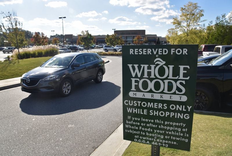 A sign warning customers their car can be towed or booted stands in the AVALON Whole Foods market parking lot. Georgia leaves it to local jurisdictions to regulate car booting. HYOSUB SHIN / HSHIN@AJC.COM