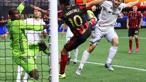Atlanta United midfielder Pity Martinez scores a goal between D.C. United goalkeeper Bill Hamid and midfielder Paul Arriola for a 1-0 lead in a soccer match on Sunday, July 21, 2019, in Atlanta. Atlanta United won the game 2-0.   Curtis Compton/ccompton@ajc.com