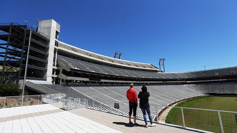 Local residents Dan Haybery and Alexis Biaggi pause to take in an empty Sanford Stadium during a walk across the University of Georgia campus from their home in downtown Athens on Thursday, April 2, 2020. Curtis Compton ccompton@ajc.com