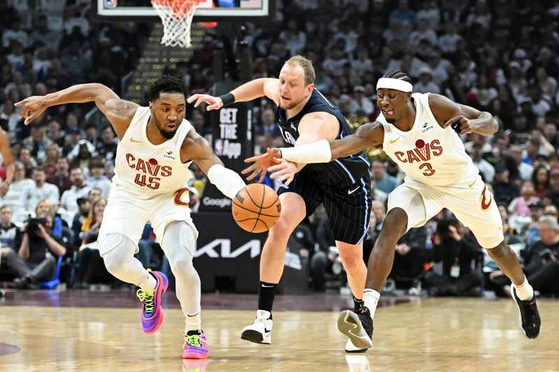 Cleveland Cavaliers' Donovan Mitchell (45) and Caris LeVert (3) steal the ball from Orlando Magic's Joe Ingles during the first half in Game 1 of an NBA basketball first-round playoff series, Saturday, April 20, 2024, in Cleveland. (AP Photo/Nick Cammett)