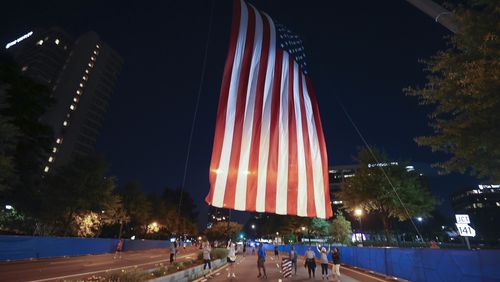 7/3/21 - Atlanta, GA - Volunteers raise the flag at the start as the AJC Peachtree Road Race returned in-person Saturday for the holiday tradition.  (Jason Getz for the Atlanta Journal-Constitution)