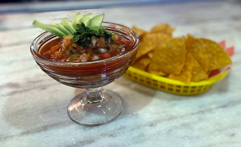 The ceviche at Dos Burros brings citrus-marinated shrimp and octopus in a thick pool of seasoned Clamato, with a garnish of avocado slices and a basket of chips. Ligaya Figueras/ligaya.figueras@ajc.com