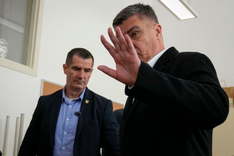 Croatia's President Zoran Milanovic, right, waves after casting his vote at a polling station in Zagreb, Croatia, Wednesday, April 17, 2024. Croatia is voting in a parliamentary election after a campaign that centered on a bitter rivalry between the president and prime minister of the small European Union and NATO member. (AP Photo/Darko Bandic)