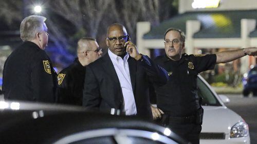 DeKalb Public Safety Director Cedric Alexander (center) speaks on the phone during Monday’s investigation. A DJ was shot and wounded early Monday, Mar. 3, 2014 during a shootout with police officers outside a popular DeKalb County nightclub, police said. The shooting happened outside the Velvet Room, a club in the 3300 block of Chamblee Tucker Road. The club was hosting an album release party Sunday night for Rick Ross and Sean “Diddy” Combs, according to the Velvet Room’s website. About 4 a.m., two off-duty officers working at the nightclub heard gunshots in the back of the club, according to DeKalb Public Safety Director Cedric Alexander. When the officers responded to the rear of the club, “one subject turned toward them, firing shots,” Alexander said. “They returned fire, hitting the subject in the leg.” The officers were uninjured, according to Alexander. He said the wounded man, who was identified to investigators as a disc jockey at the club, got up and went back inside the club, where he was arrested before being transported to Grady Memorial Hospital. “For whatever unknown reasons, it appears that this DJ who was involved in the shooting with some others turned and shot at the officers, and that’s when they returned fire,” Alexander said. He said the off-duty officers were in full uniform, and identified themselves as officers when they responded to the gunfire behind the club. “They were doing what they were trained to do,” Alexander told The Atlanta Journal-Constitution. JOHN SPINK/JSPINK@AJC.COM