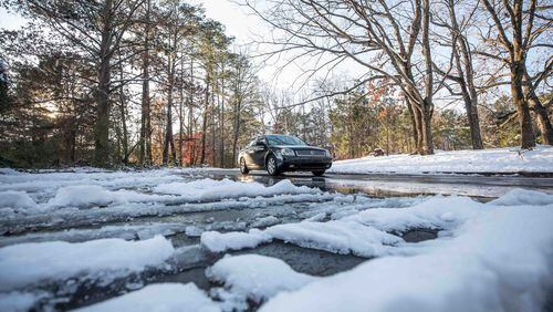 A car drives on a wet road in Kennesaw that is partially covered in ice and snow on Sunday, Dec. 10, 2017. Parts of Cobb County saw up to a foot of snow from the storm that moved into the area on Friday and continued into Saturday. Commuters face the risk of black ice on roadways Monday morning. BRANDEN CAMP / SPECIAL TO THE AJC