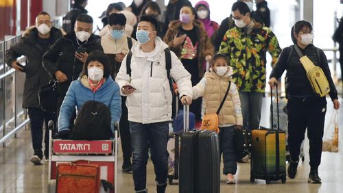 Passengers wear masks at Beijing international airport on Jan. 24, 2020, the first day of the Lunar New Year holiday, amid the spread of pneumonia caused by a new coronavirus believed to have originated in the central Chinese city of Wuhan. (Kyodo via AP Images) ==Kyodo
