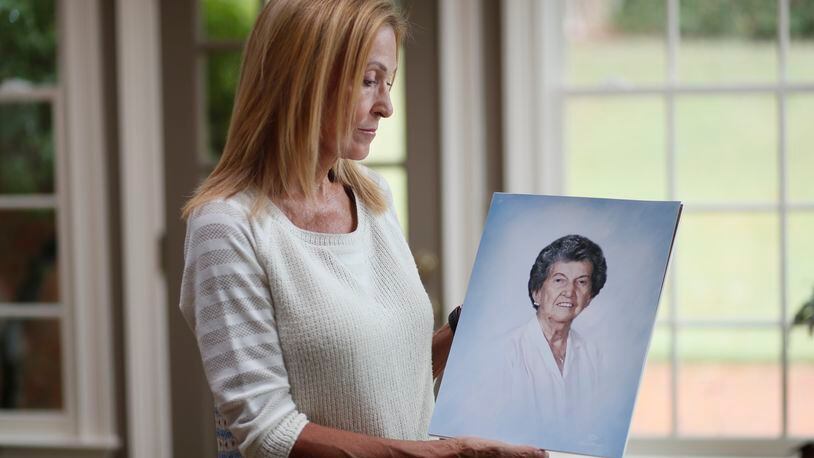 Gail Walker with a photo of her mother, Lucile McMichael Brown, who died in 2015 at age 92. Her mother was a resident of an assisted living home in Macon. Her mother apparently got up in the night and somehow went out a door that was supposed to sound an alarm to alert staff if someone opened it. But no one noticed that Brown went out the door, fell down a hill and died. She was found outside after staff noticed she was not in her room. (Bob Andres / robert.andres@ajc.com)