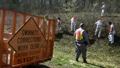 In this 2002 AJC file photo, inmates from the Gwinnett Department of Corrections work detail works alongside Ronald Reagan Parkway in Lilburn. FILE PHOTO