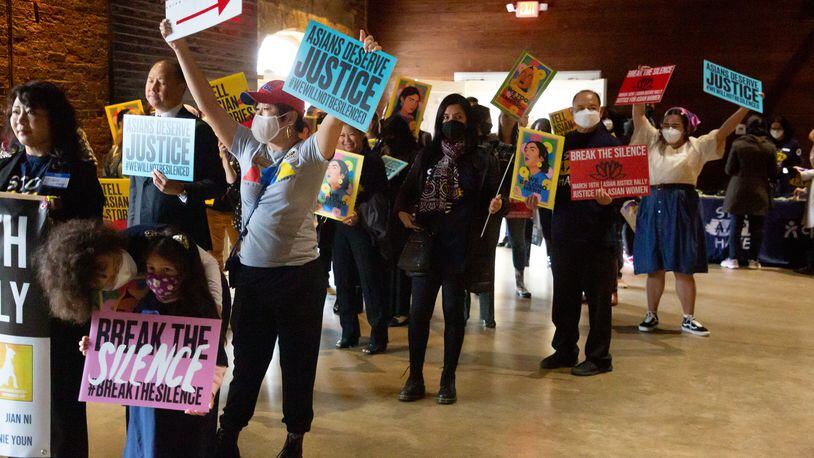 Participants at the Georgia Freight Depot wave signs at the beginning of the Asian Justice 1-year anniversary of the spa shootings rally in Atlanta on March 16, 2022.   STEVE SCHAEFER FOR THE ATLANTA JOURNAL-CONSTITUTION