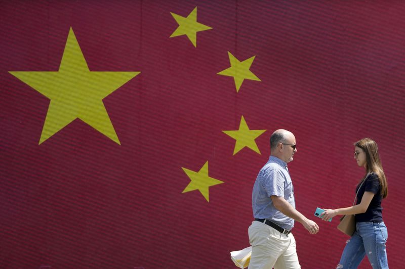 People walk in front of a Chinese national flag in Belgrade, Serbia, Tuesday, May 7, 2024. Chinese leader Xi Jinping's visit to European ally Serbia on Tuesday falls on a symbolic date: the 25th anniversary of the bombing of the Chinese Embassy in Belgrade during NATO's air war over Kosovo. (AP Photo/Darko Vojinovic)