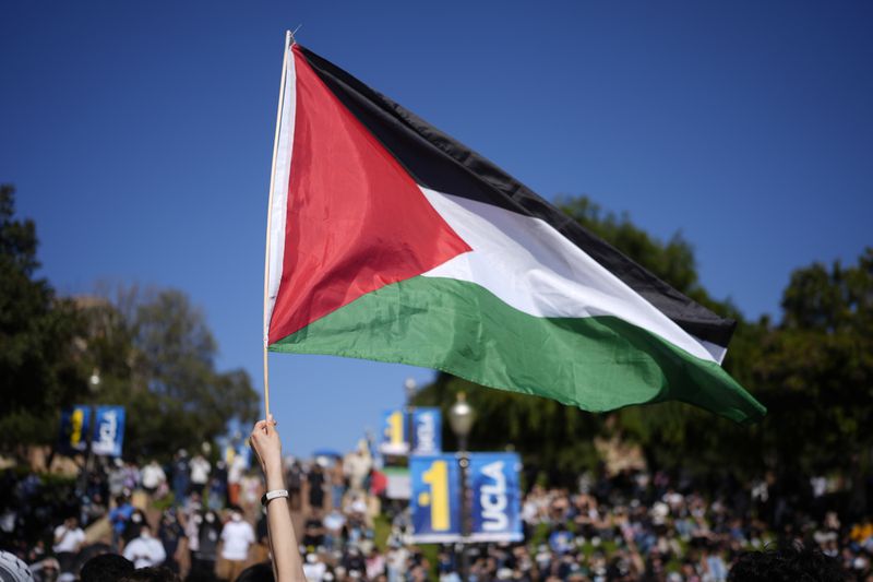 A Palestinian flag is waved as protesters gather on the UCLA campus, after nighttime clashes between Pro-Israel and Pro-Palestinian groups, Wednesday, May 1, 2024, in Los Angeles. (AP Photo/Jae C. Hong)
