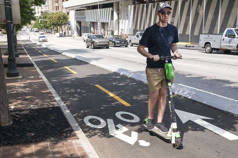 A man rides a shareable electronic scooter in the bike lane along Centennial Olympic Park Drive. (Alyssa Pointer/alyssa.pointer@ajc.com)