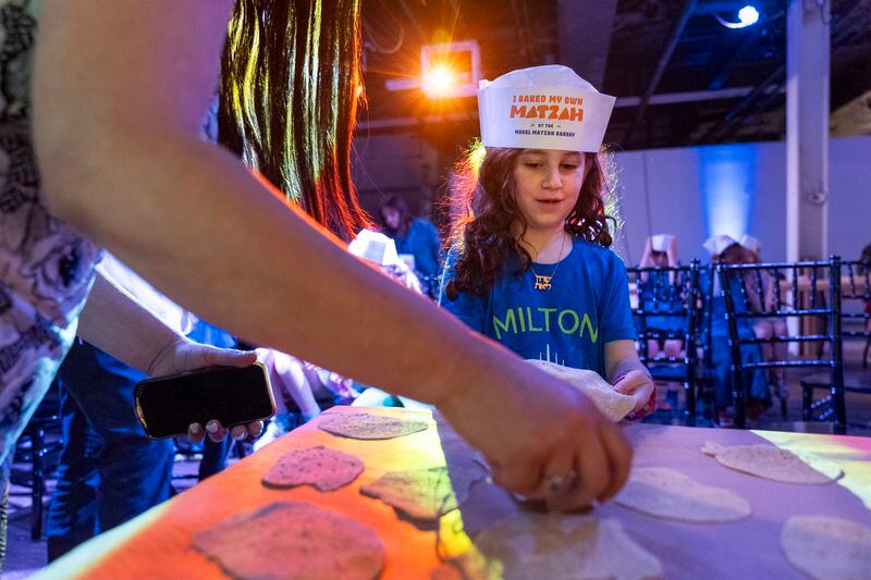 Charlotte Gleicher, 7, a first grader at Milton Gottesman Jewish Day School of the Nation's Capitol, brings up dough to be baked into matzah that she made during a "Matzah Factory" event at the JCrafts Center for Jewish Life and Tradition in Rockville, Md., Thursday, April 18, 2024, ahead of the Passover holiday which begins next Monday evening. To be kosher for Passover, which begins next Monday evening, the dough has to be prepared and cooked all within 18 minutes and not allowed to rise. (AP Photo/Jacquelyn Martin)