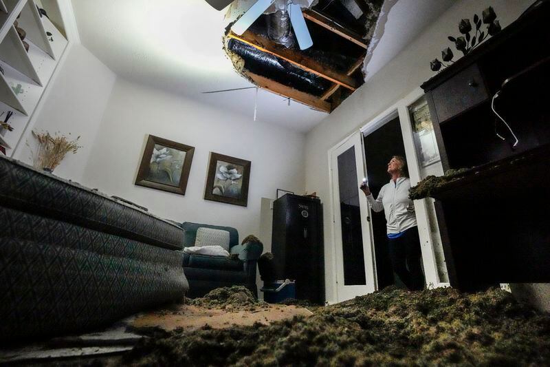 Monica Pease surveys the damage of the office space inside her home, where she was working when several trees fell on it, collapsing the ceiling, during a severe storm, Thursday, May 2, 2024, in Spring, Texas. (Brett Coomer/Houston Chronicle via AP)