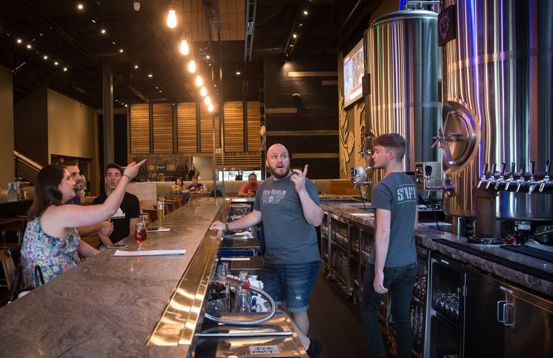 Bartender Stephen Horton (center) explains the brewing process to customers at the New Realm Brewing restaurant in Atlanta. STEVE SCHAEFER / SPECIAL TO THE AJC