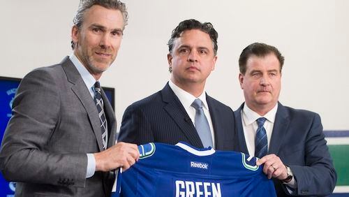 In this April 26, 2017, file photo, Vancouver Canucks president Trevor Linden, left, and general manager Jim Benning, right, introduce the Canucks new head coach Travis Green during a news conference in Vancouver, British Columbia. Three of the six NHL coaching vacancies this offseason were filled by first-timers as teams look to find the next new idea rather than recycling the past.  (Jonathan Hayward/The Canadian Press via AP, File)