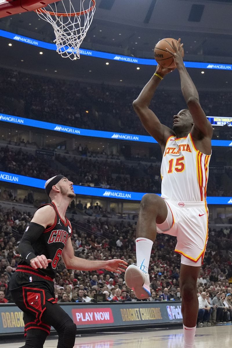 Atlanta Hawks center Clint Capela, right, drives to the basket against Chicago Bulls guard Alex Caruso during the first half of an NBA basketball play-in tournament game in Chicago, Wednesday, April 17, 2024. (AP Photo/Nam Y. Huh)