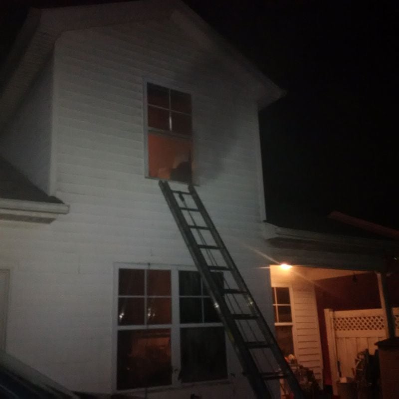Fire crews used a ladder to help a woman hanging out a second-story window to escape a house fire on Pine Village Place near Loganville. (Photo: Gwinnett County Fire Department)