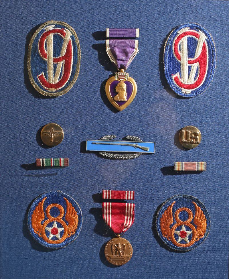 Some of Eddie Sessions' medals and badges, including the Purple Heart (top row center) and the emblem of the 95th Infantry Division (top row right and left).