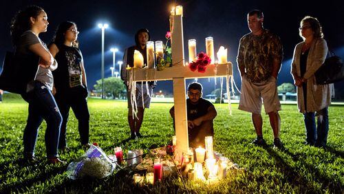 Mourners visit one of 17 crosses after a candlelight vigil for the victims of the shooting at Marjory Stoneman Douglas High School in Parkland on Thursday. (Greg Lovett / The Palm Beach Post)
